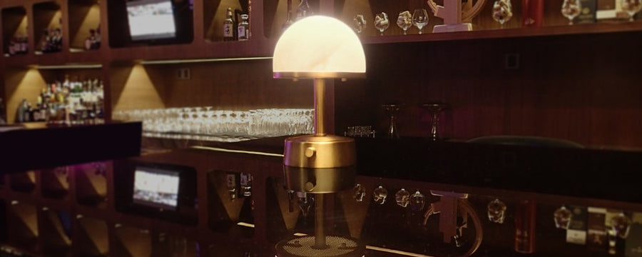 Stylish mini cordless lamps for hospitality illuminating a modern bar setting with a warm glow.