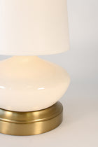 Table lamp with white shade and gold base on a light gray background