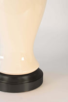 Close-up of a cordless lamp with an ivory ceramic and black base that holds battery pack
