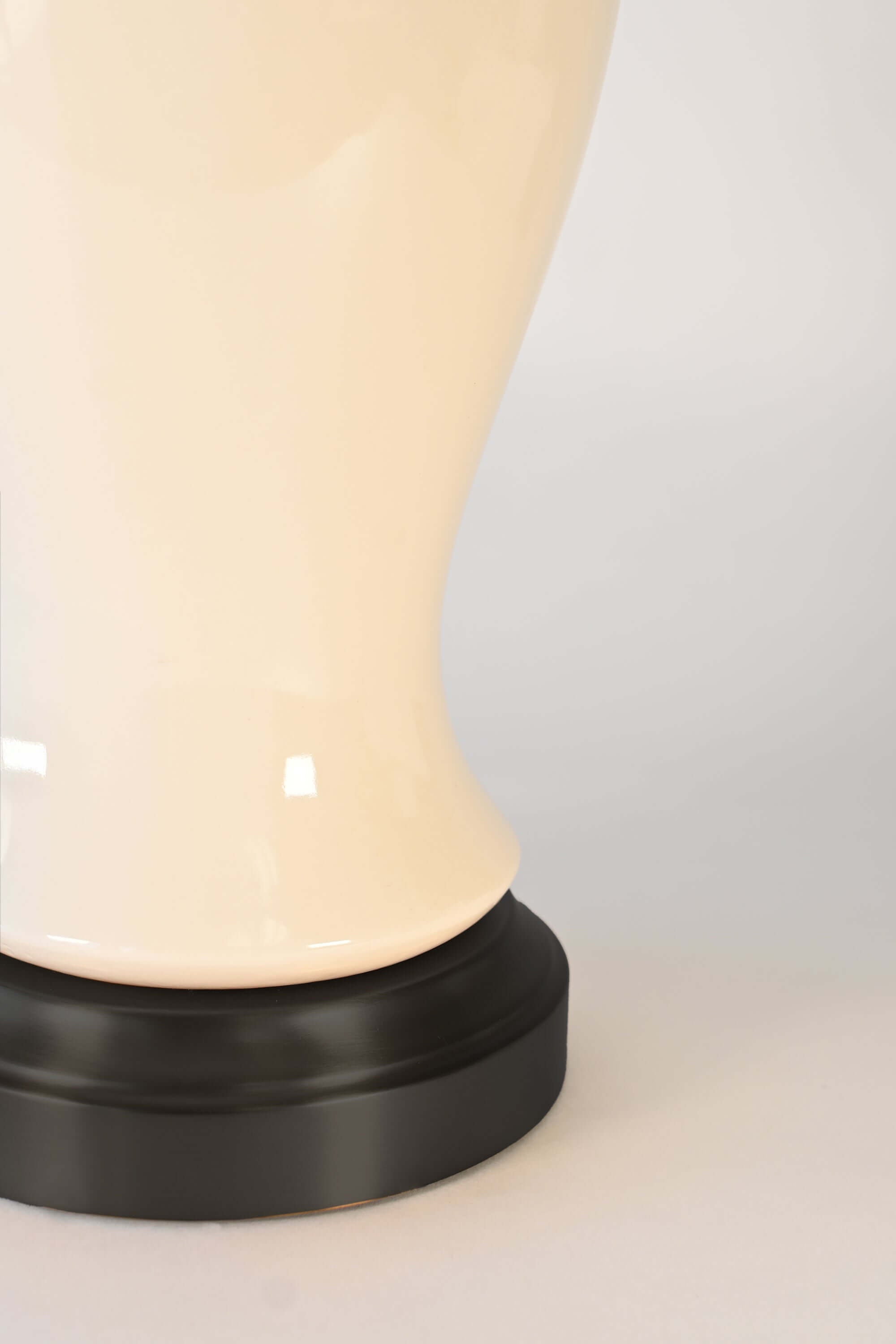 Close-up of a cordless lamp with an ivory ceramic and black base that holds battery pack
