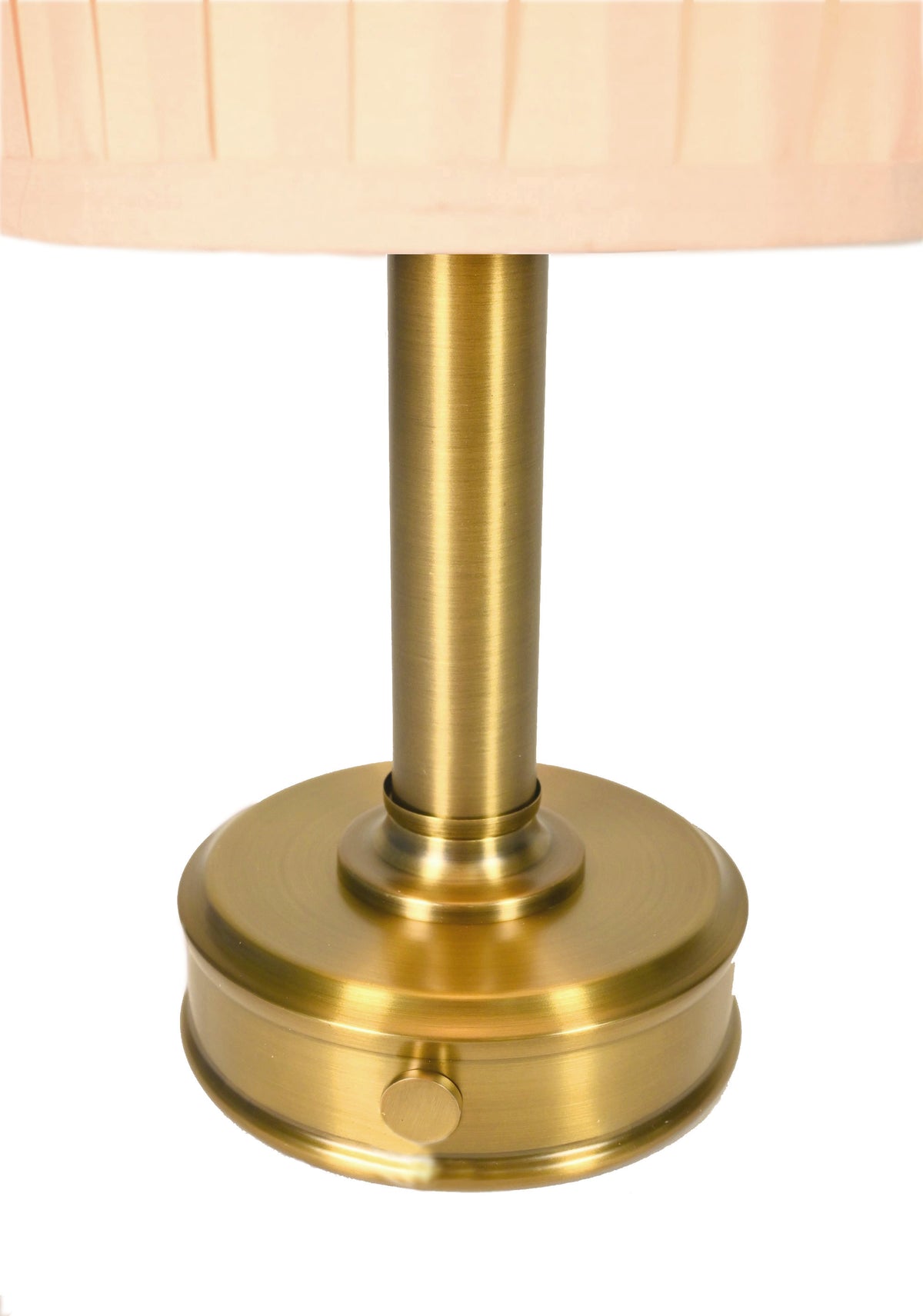 Close-up of a cordless table lamp with a round brushed brass base and a pleated light beige fabric shade by modern lantern