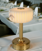 Decorative cordless mini lamp with marble-like shade and gold base on a table.