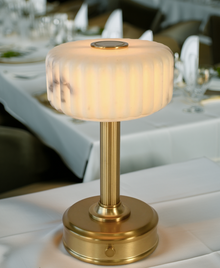 Decorative cordless mini lamp with marble-like shade and gold base on a table.