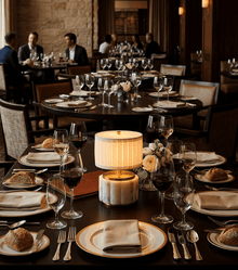 Nora rechargeable mini lamp illuminating a dining table set in an elegant restaurant, with wine glasses and plates.