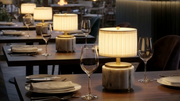 Mini Nora rechargeable mini lamp on restaurant tables, featuring antique brass and pleated shade for elegant dining.