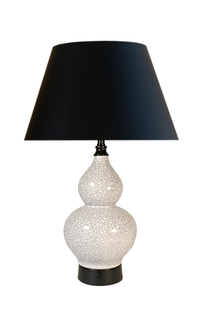 A cordless table lamp with a black tapered fabric shade, a glossy white ceramic gourd-shaped base featuring a crackle glaze pattern, and a black metal base.