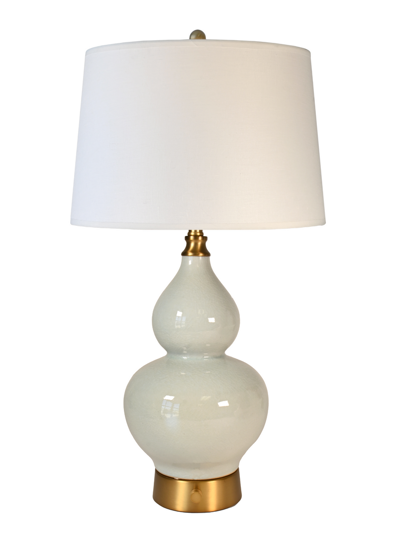 A cordless table lamp with a glossy light sage gourd-shaped ceramic base, an ivory tapered drum shade, and brass-finished metal accents at the neck and bottom.
