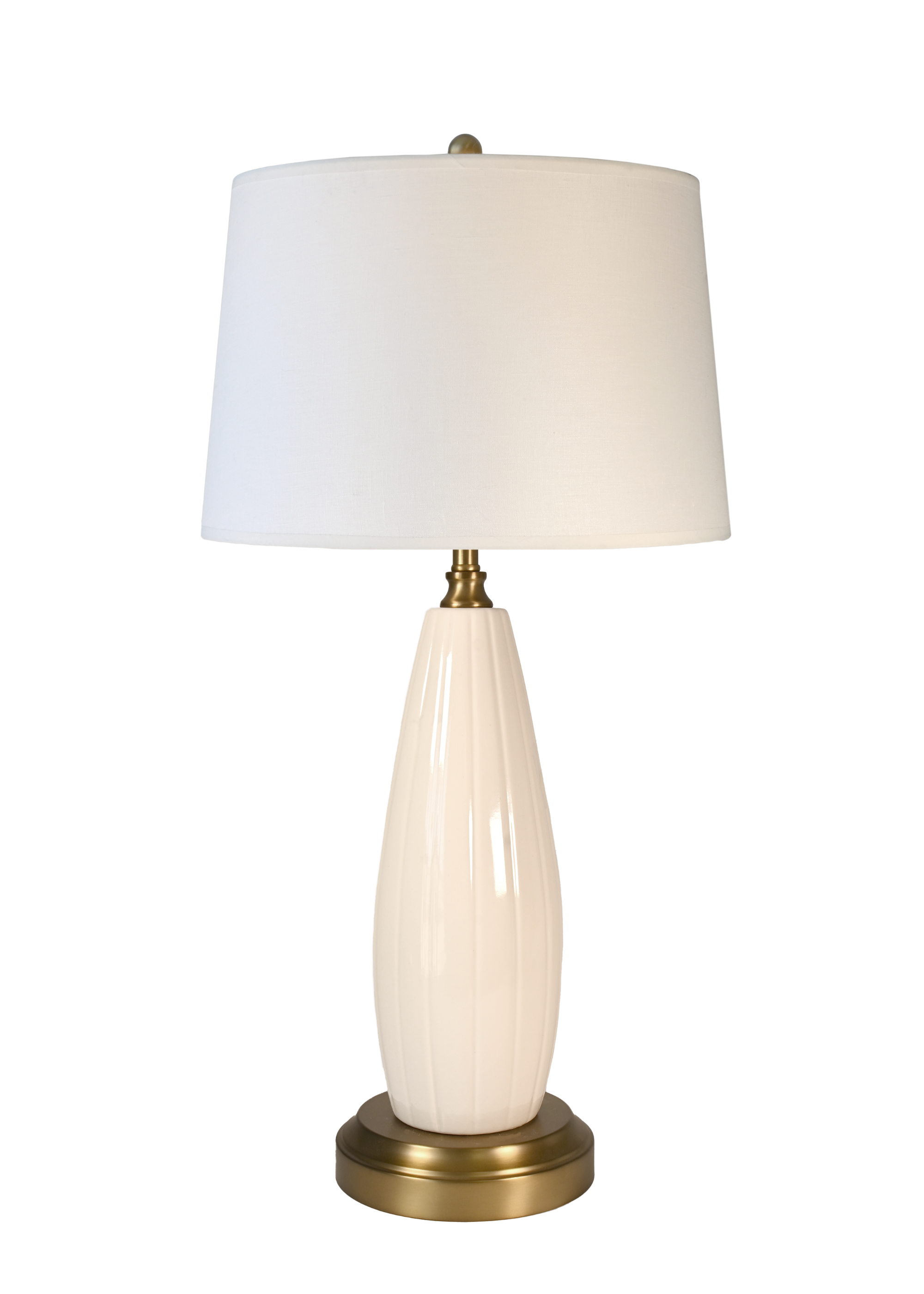A cordless table lamp with an off white drum shade, a glossy cream ribbed ceramic base, and a brass-finished metal neck and circular base