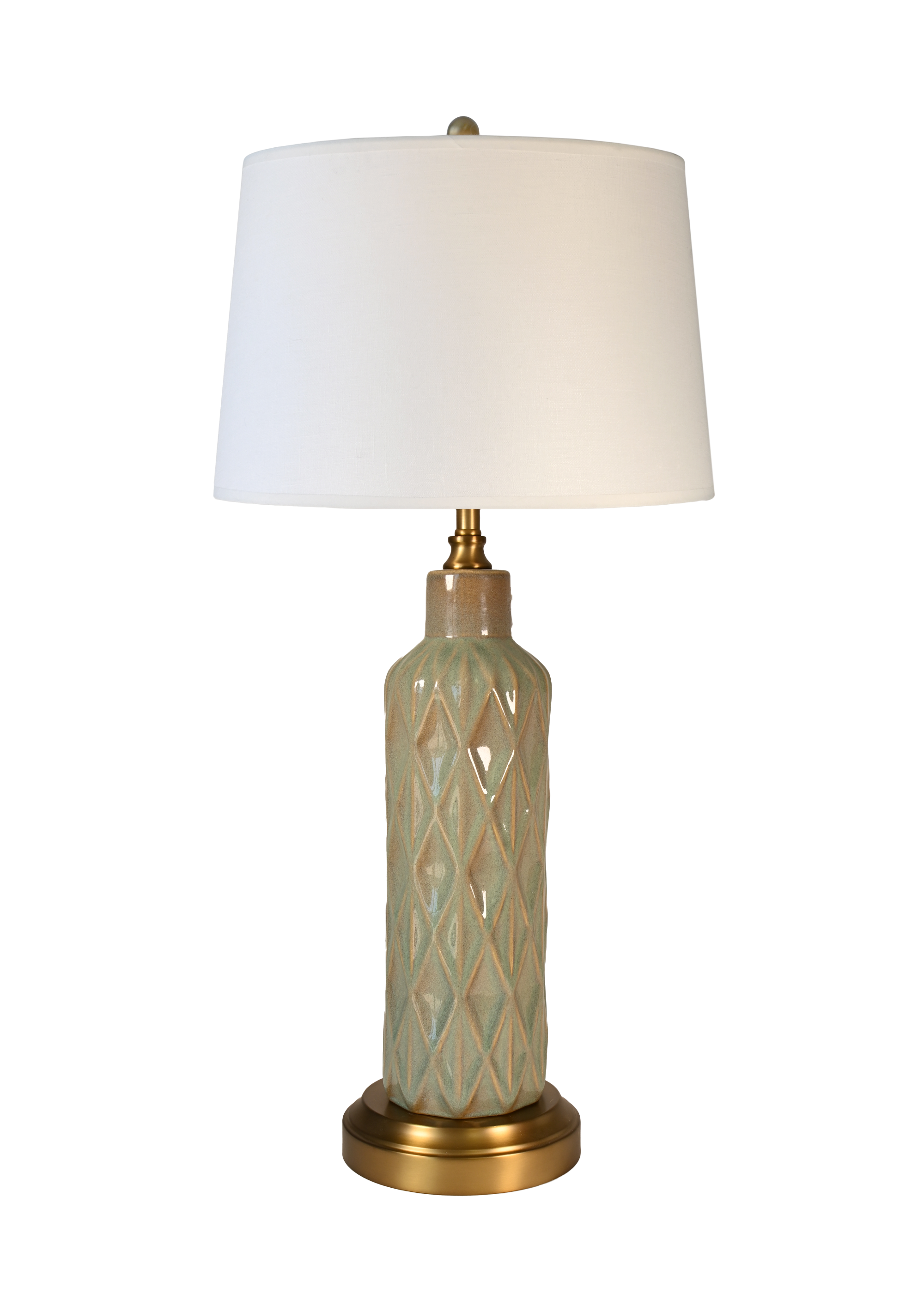 A cordless table lamp with an off white drum shade, a textured ceramic base in a pale sage green and beige diamond pattern, and a gold-finished neck and base.