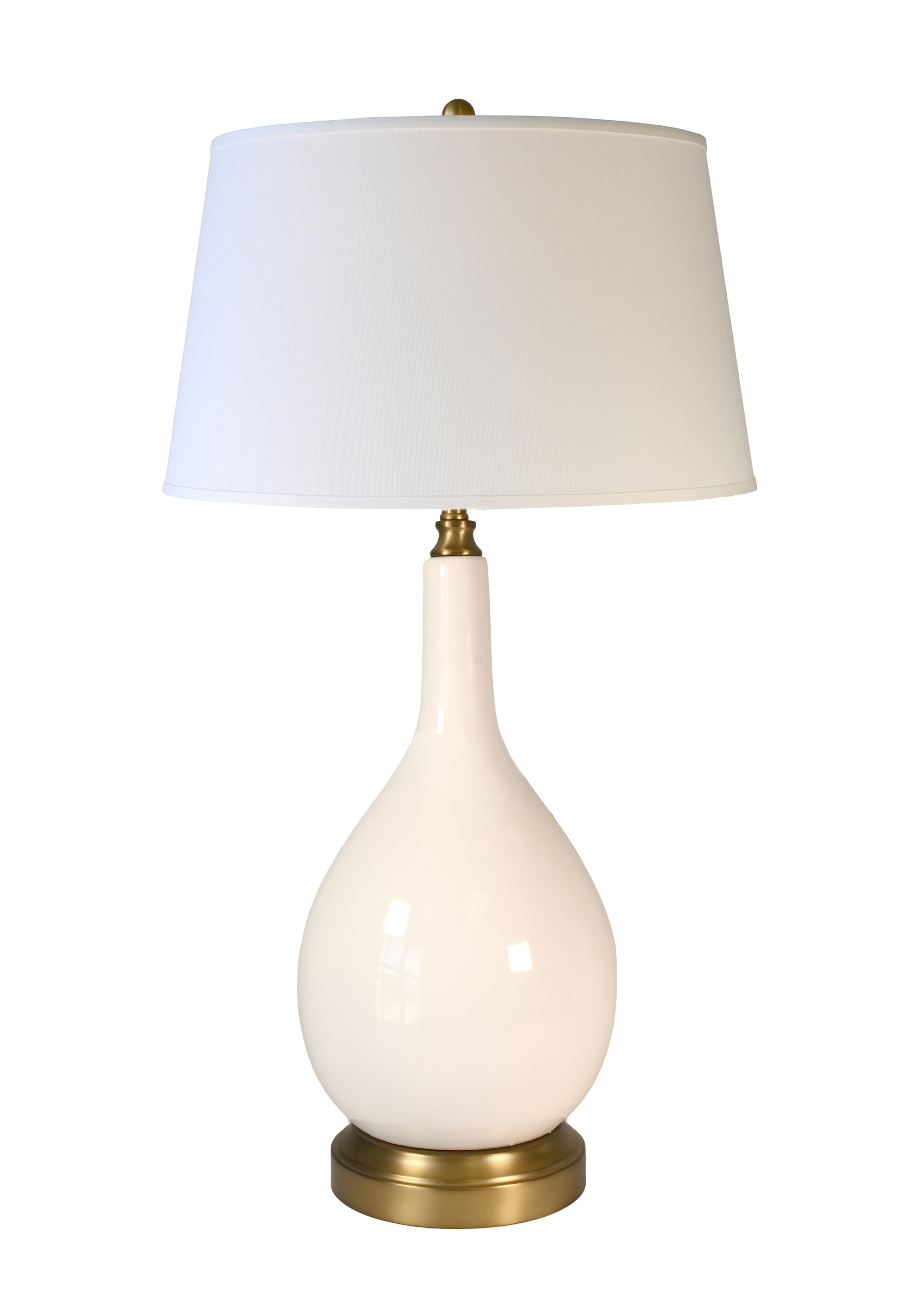 A large cordless table lamp with a glossy ivory teardrop-shaped ceramic base, an off white drum shade, and brass-finished metal accents at the neck and bottom.