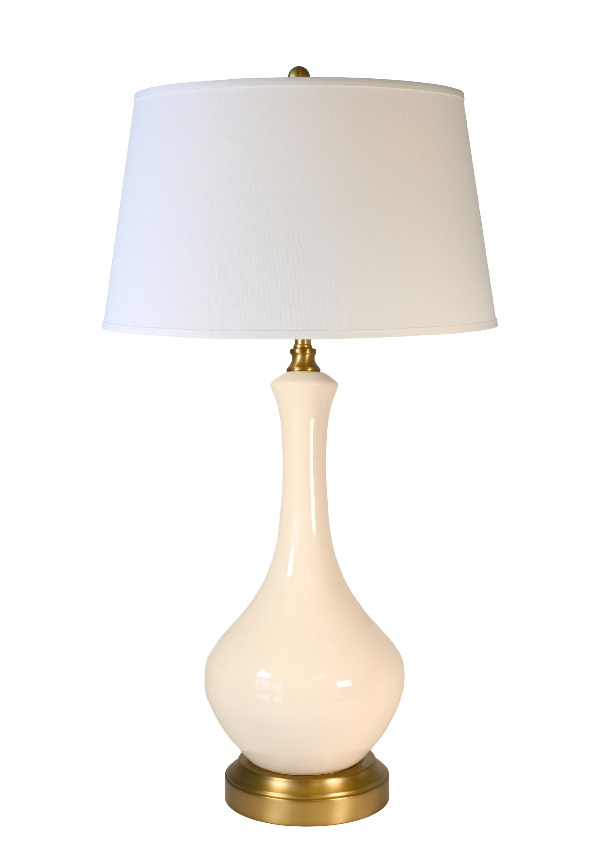 A cordless table lamp with a glossy cream-colored ceramic vase-shaped base, an off white fabric drum shade, and brass-finished metal accents at the top and bottom.