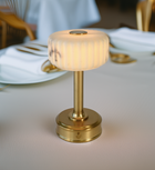 Small battery operated table lamp with gold base and white marble shade in luxury restaurant