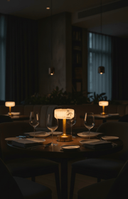 Dining table fine restaurant with wine glasses and a cordless minilamp in a dimly lit room